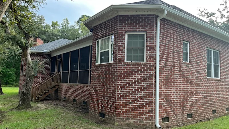 Gutter installation around bay window on brick house in Wadmalaw Island, SC.